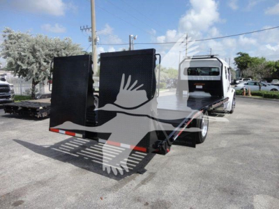 Freightliner Business Class M2 rollback truck with a flatbed and a hinged cargo bed in a dealership lot.