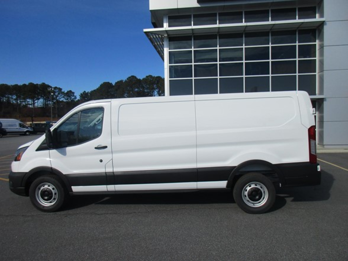 Ford Transit cargo van in white side profile view showing blank side panels and windows, exterior fuel door, front cab, and rear cargo area.