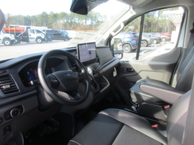 Interior view of 2026 Ford Transit cargo van showing steering wheel, dashboard with touchscreen display, and front seats.