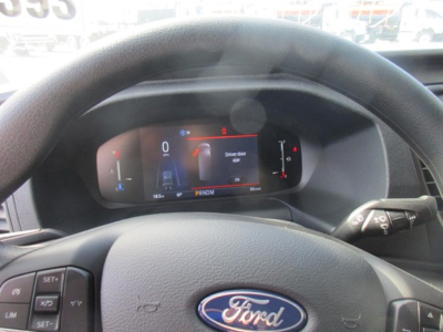 Ford Transit cargo van interior showing digital instrument cluster with steering wheel and dashboard controls.