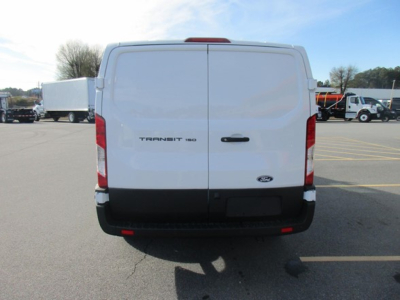 Ford Transit 250 cargo van rear view showing twin rear doors with Ford emblem and Transit badge; parking lot with other trucks in background.