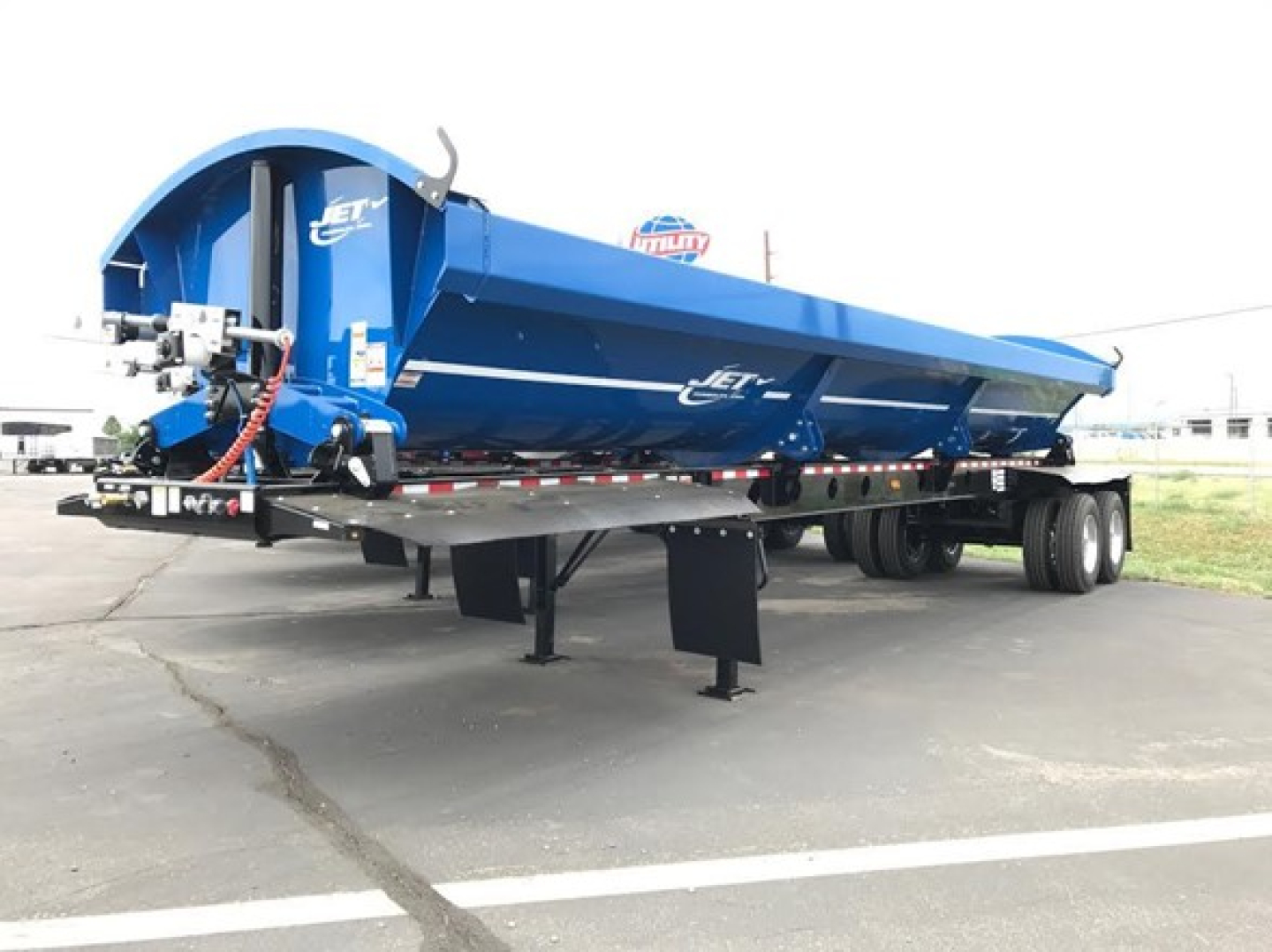 Blue Jet side dump trailer showing hydraulic dump mechanism and tandem rear axles.