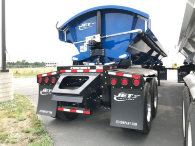 Jet Jet Side Dump trailer in blue mounted on a black chassis with rear lights and mud flaps, branding visible on fenders.