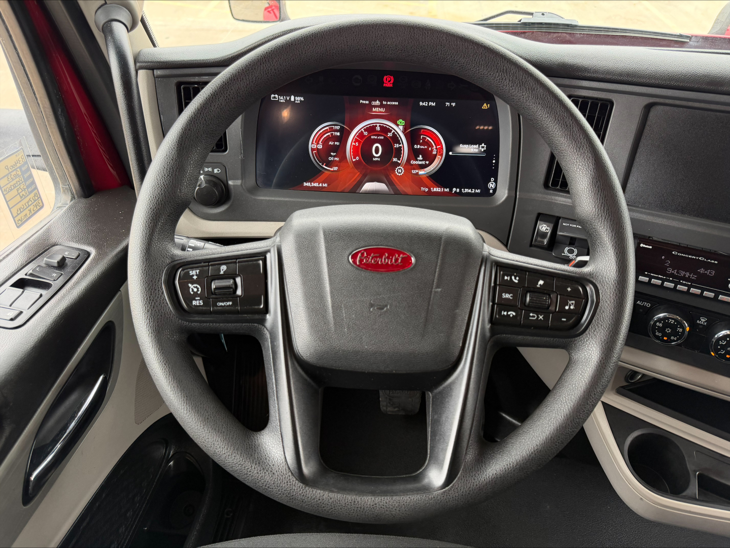 Peterbilt interior steering wheel and dash showing digital gauges and controls in driver seat view.