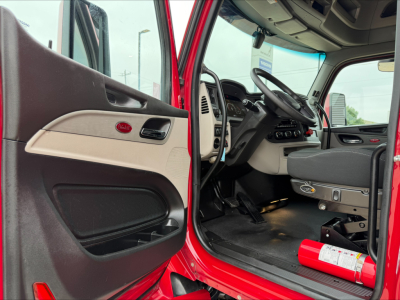 Peterbilt 579 cab interior showing steering wheel, dashboard, and driver door with red exterior.