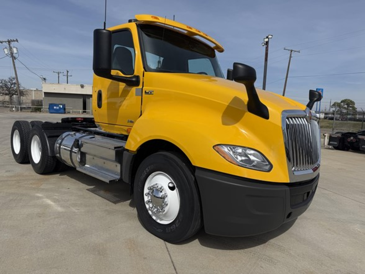Truck image showing a yellow 2019 International LT625 Daycab with six wheels, chrome front grille, and black bumper.