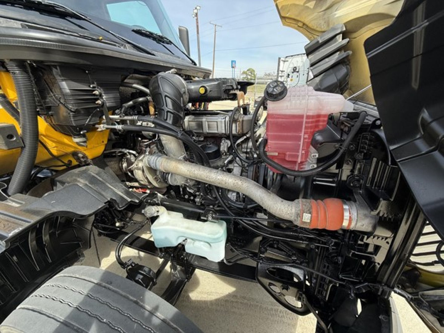 International LT625 engine bay showing coolant reservoir, reservoir caps, hoses, and engine components.