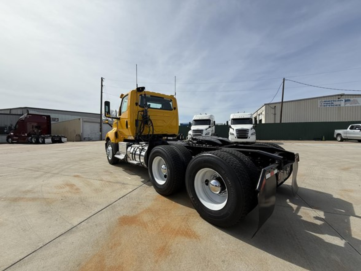 2019 International LT625 truck chassis rear view showing dual rear axles and yellow cab with black chassis in a lot.
