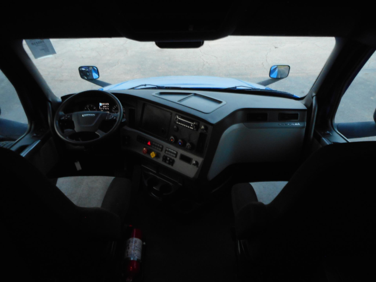 Dashboard and steering wheel view inside a Freightliner Cascadia cab showing dash controls and windshield, front seats visible.