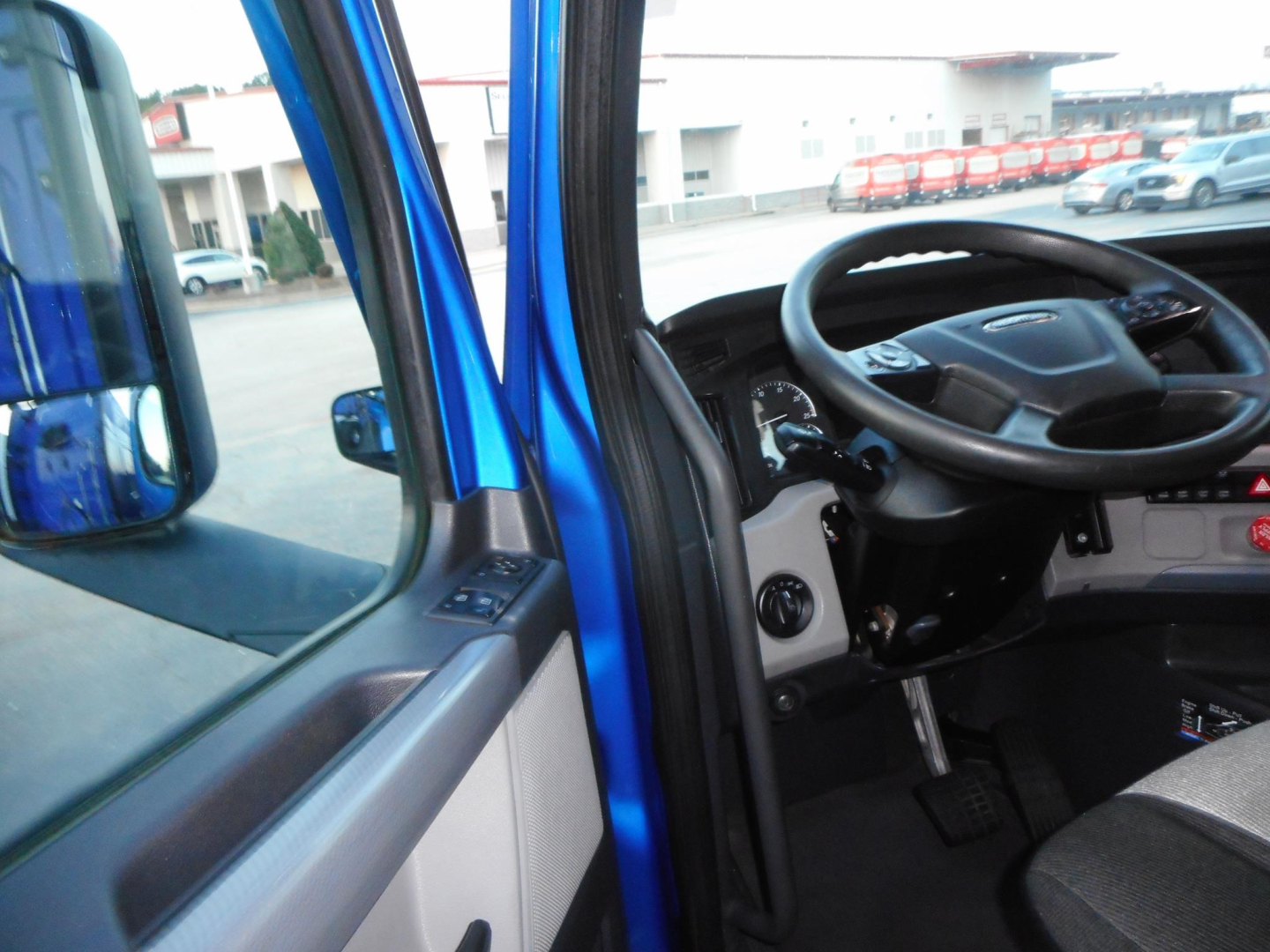 Cabin interior of a Freightliner Cascadia 126 truck showing steering wheel and driver's side door area