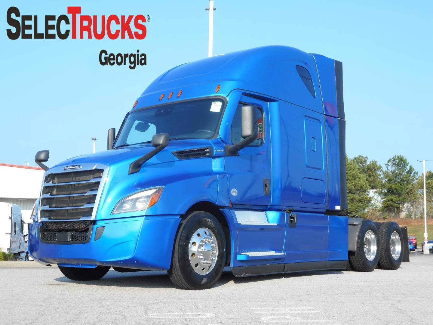 Blue Freightliner Cascadia 126 tractor in a parking lot, front three-quarter view with trailerless chassis.