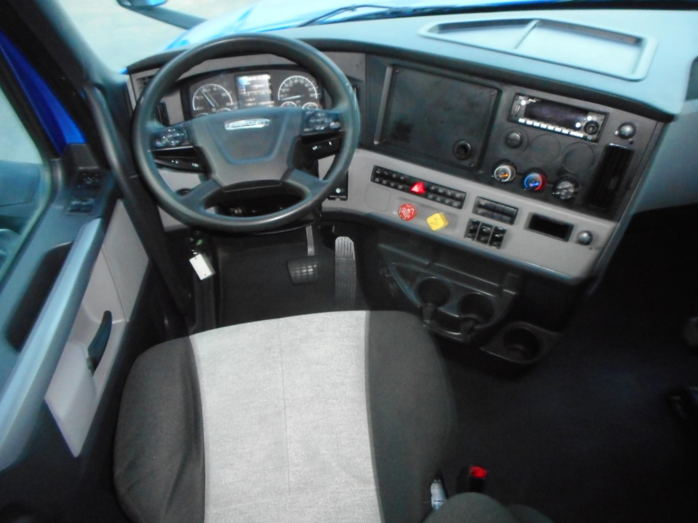 Freightliner Cascadia truck interior showing steering wheel and dashboard with gauges and controls.