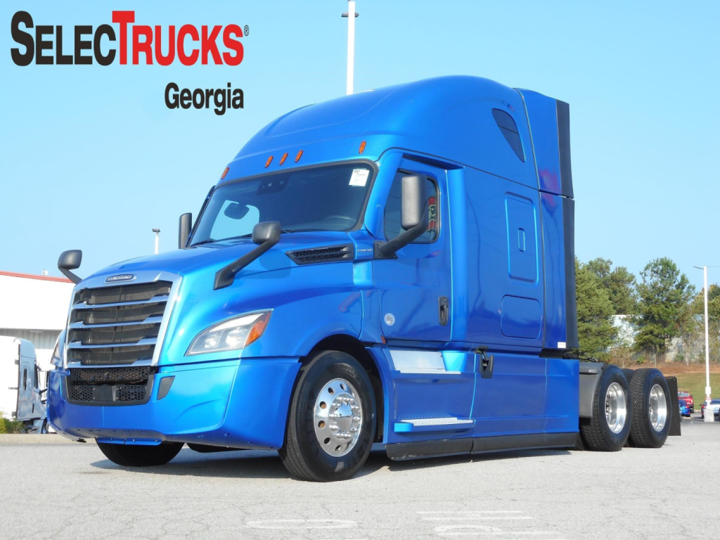 Blue Freightliner Cascadia 126 tractor in a parking lot, front three-quarter view with trailerless chassis.