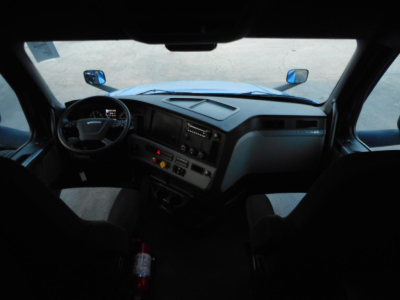 Dashboard and steering wheel view inside a Freightliner Cascadia cab showing dash controls and windshield, front seats visible.