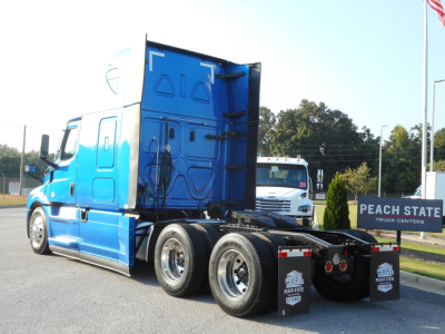 Truck rear view showing Freightliner Cascadia 126 tractor with blue cab and dual rear axles, chrome wheels, and hitch area.