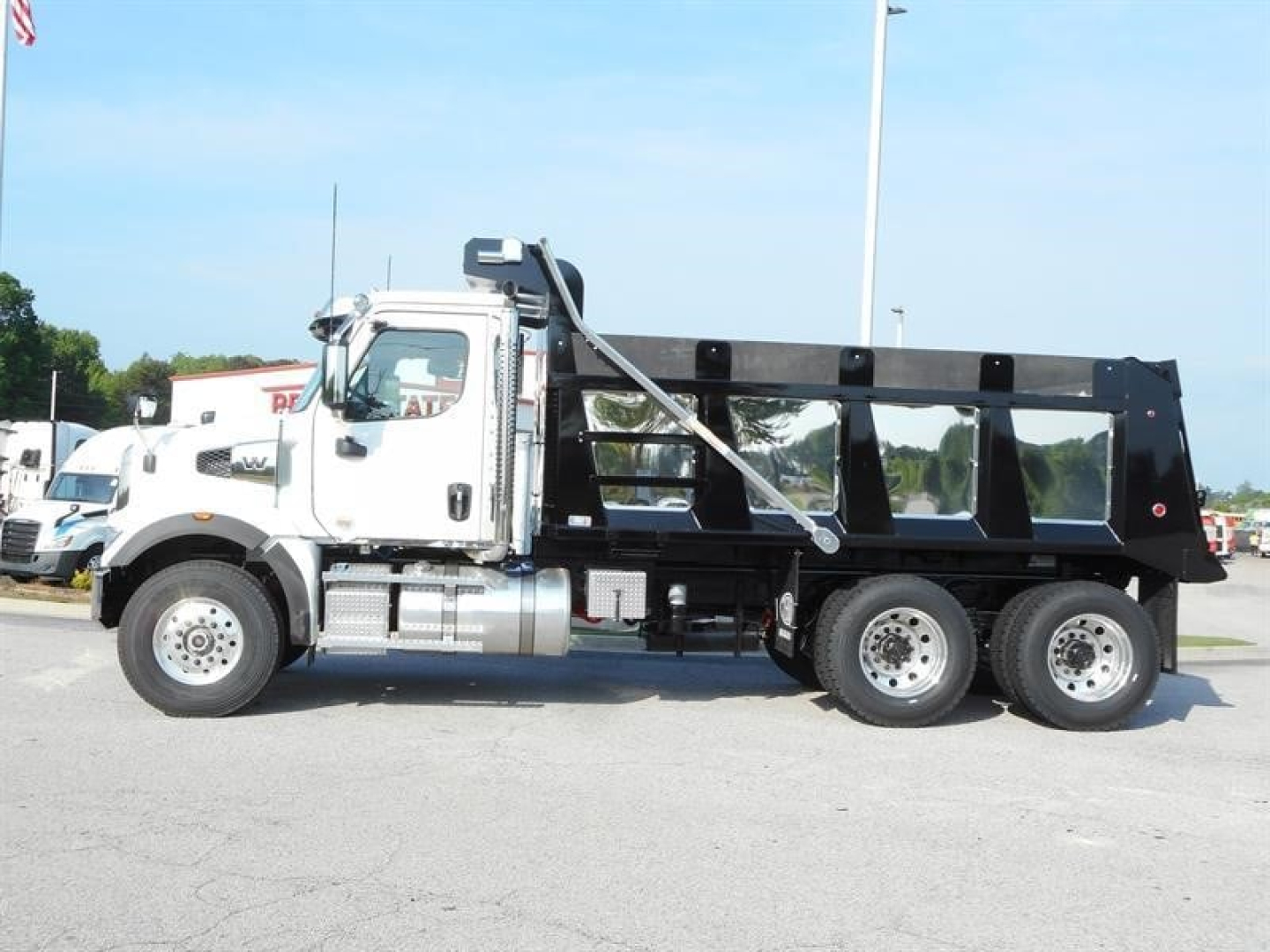 Western Star 47X dump truck side view showing cab and black dump bed with tandem rear axles.