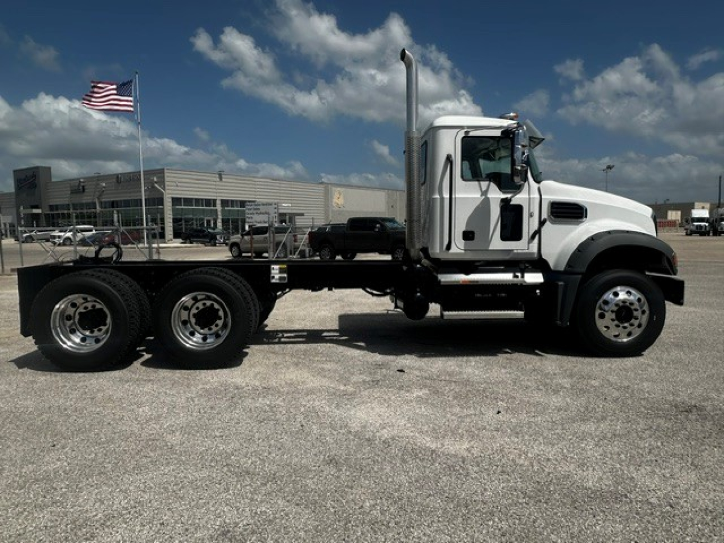 Mack GR64F dump truck side view showing chassis and cab with exhaust stack and dual rear axles.