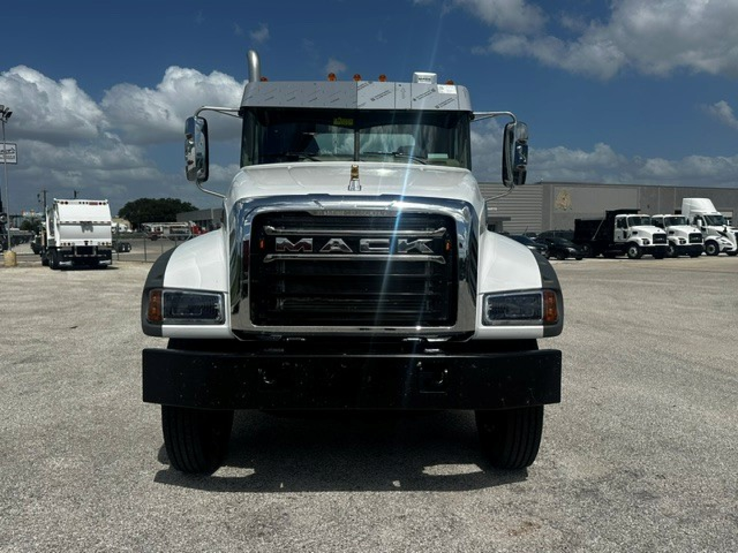 Front view of a white 2027 Mack GR64F dump truck showing grille, headlights, and bumper.