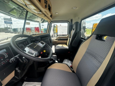 Truck cabin interior of a new 2027 Mack GR64F showing driver seat and dashboard with steering wheel and controls.