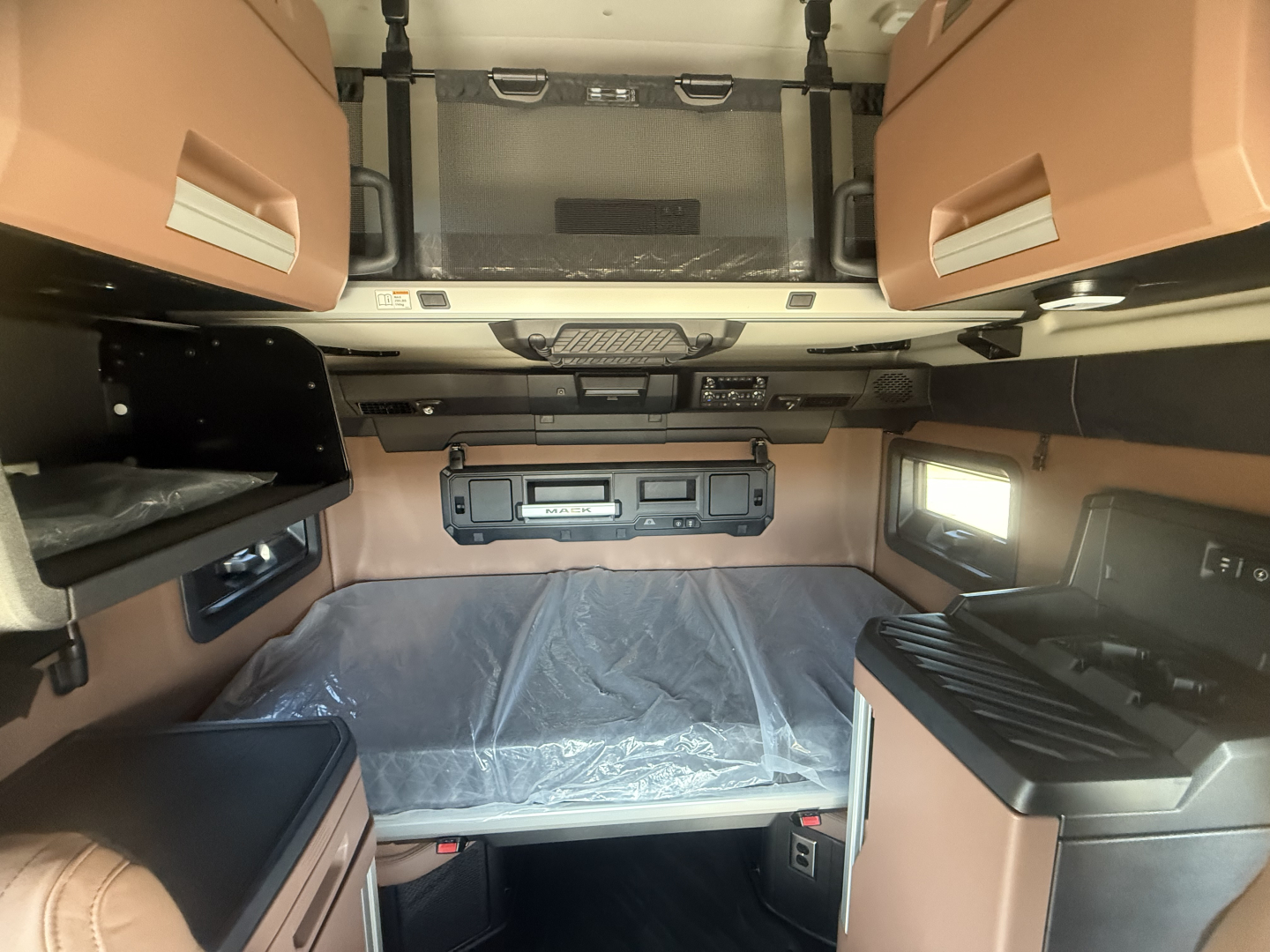 Truck cab interior showing sleeper area with overhead cabinets, dashboard area, and side panels.