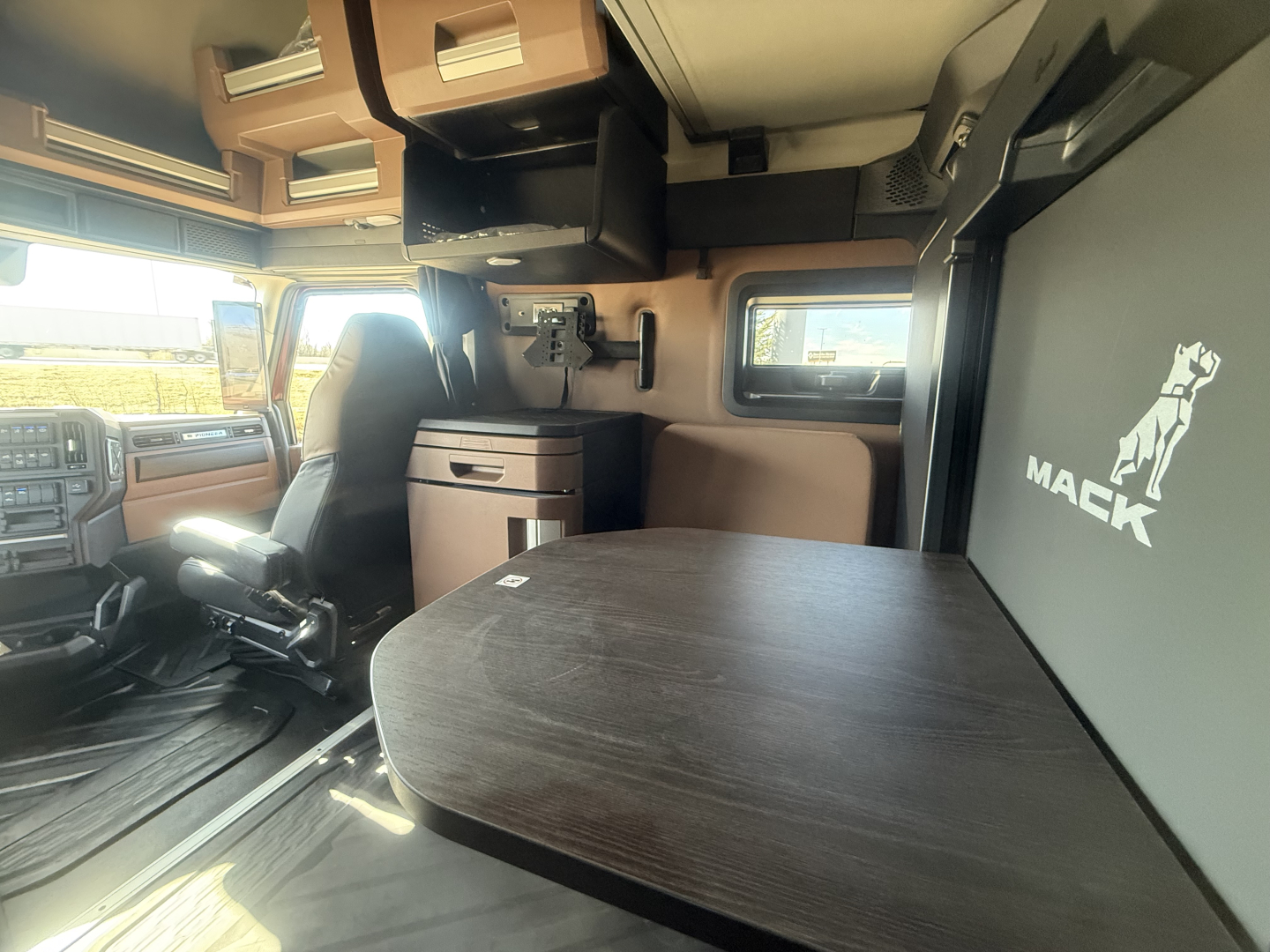 Mack PR64T76H truck interior cabin with table, cabinets, and logo panel showing Mack branding.