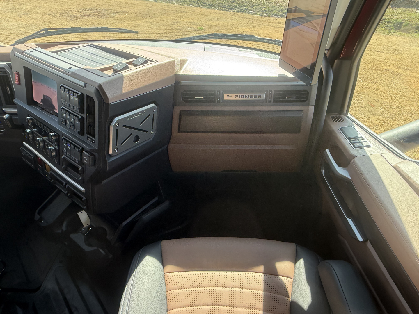 Interior of a 2026 Mack PR64T76H truck cab showing dashboard controls and Pioneer radio, tan seats, and steering area.