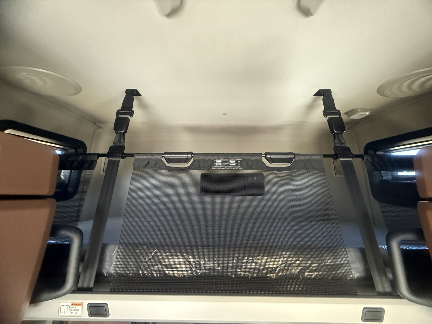 Mack PR64T76H sleeper cab interior showing overhead bunk area with safety straps and storage net.