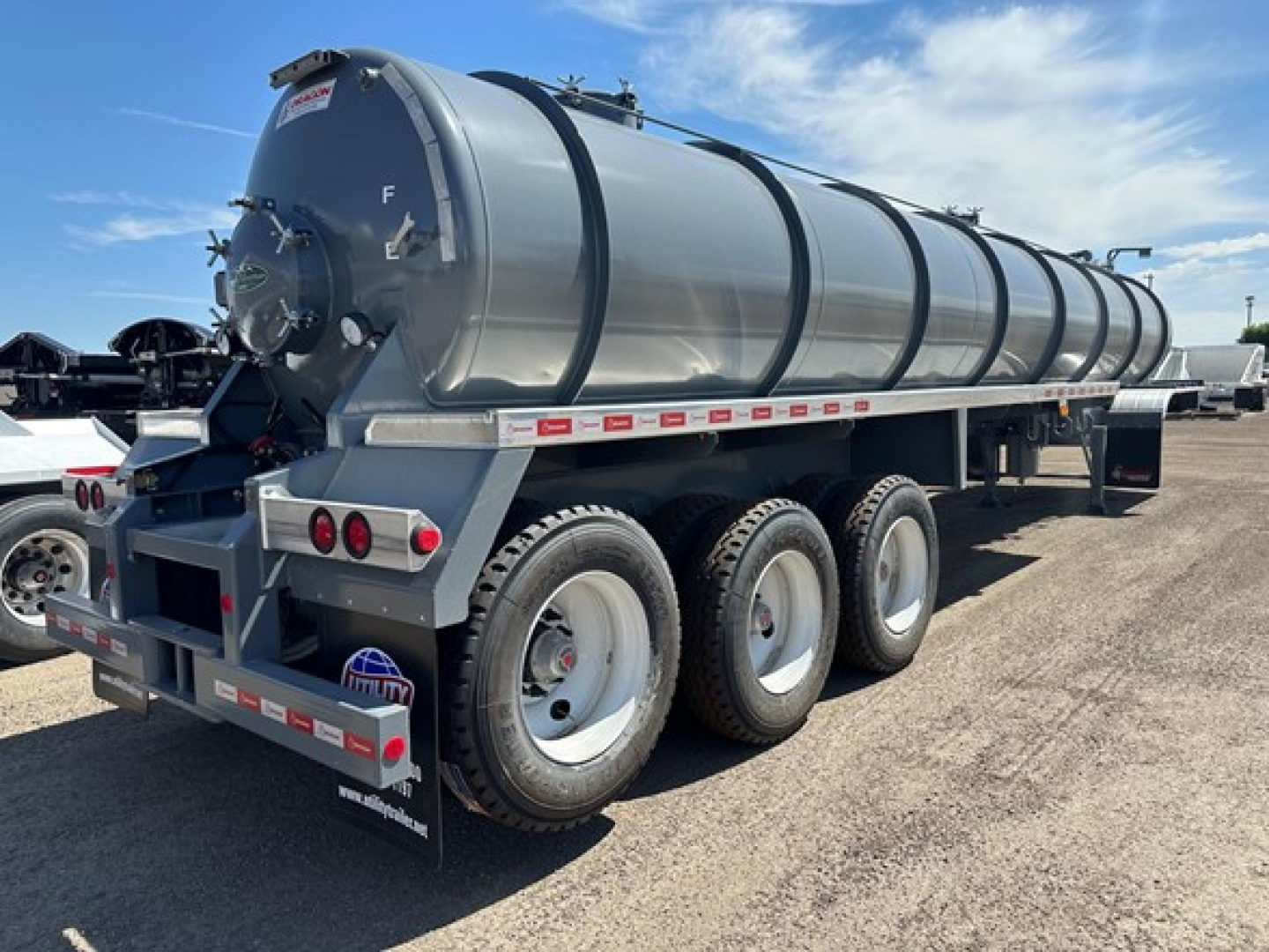 Vacuum water tank trailer with three-axle rear, cylindrical tank, metal frame, and rear access hatch showing light fixtures and reflective tape.