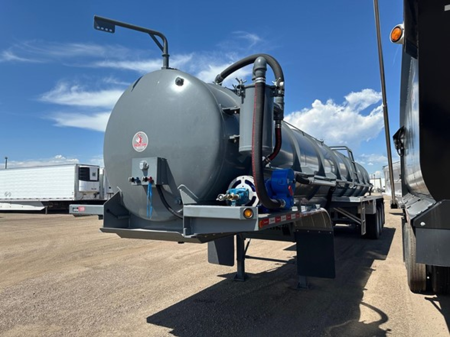 Tank trailer showing vacuum water tank with circular end cap, rear access hatch, hoses, and mounting brackets on a support frame.