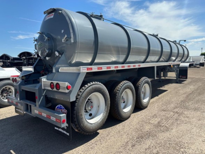 Vacuum water tank trailer with three-axle rear, cylindrical tank, metal frame, and rear access hatch showing light fixtures and reflective tape.