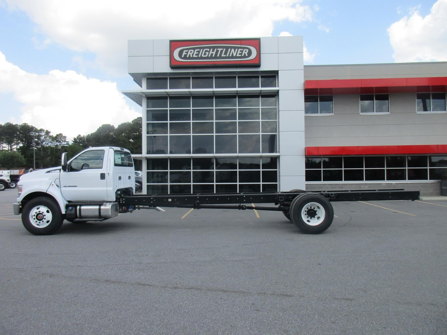 Ford F750 SD cab and chassis truck in parking lot with Freightliner dealership building in background