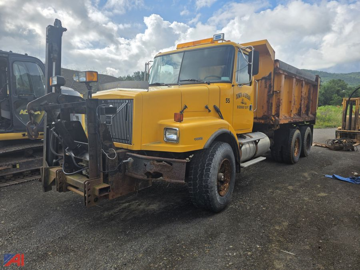 Volvo WG dump truck with sander body in yellow, front view showing snow plow mount and large grille, 6x4 configuration, worn front bumper and dump bed.