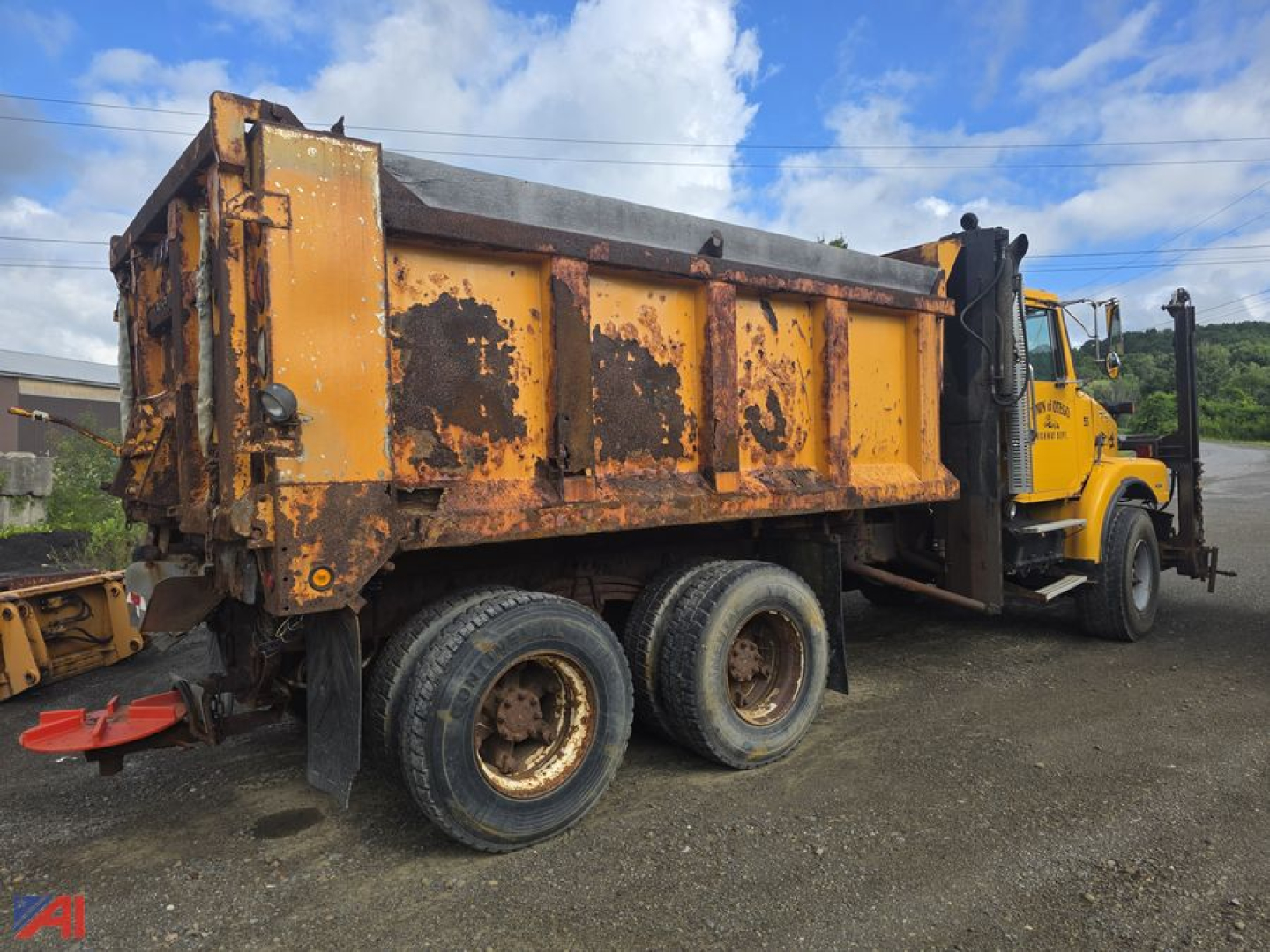 Dump truck side view showing a yellow Volvo WG dump body with a three-axle configuration and a rusty, weathered hopper.