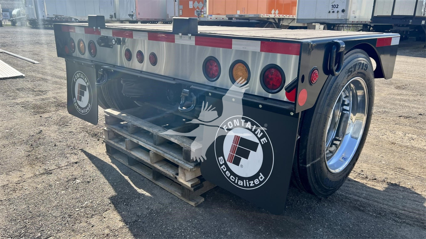 Fontaine Renegade lowboy trailer rear view showing rear lights, reflective tape, dual wheels, and branded mud flaps with Fontaine Specialized logo.