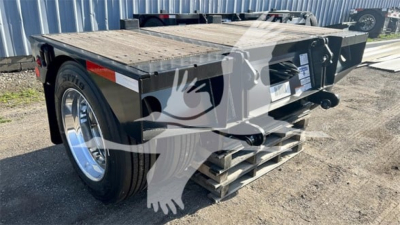 Fontaine flip axle trailer deck rear view showing safety chain and wooden deck edge with ramps folded under.