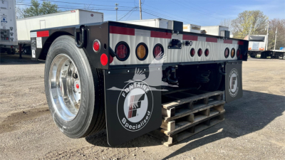 Fontaine Renegade lowboy trailer showing rear wheel, heavy-duty steel frame, multiple circular taillight housings, and brand decals.
