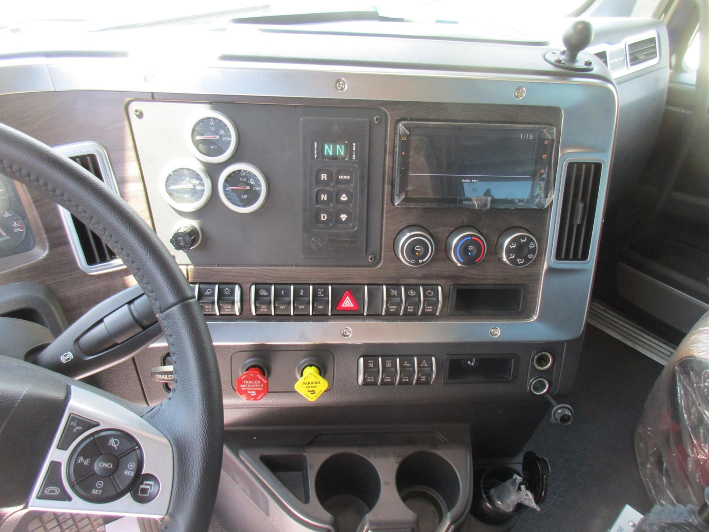 Dashboard view of a Western Star 49X cab showing instrument gauges, center control panel, climate controls, hazard switch, and red/blue knobs.