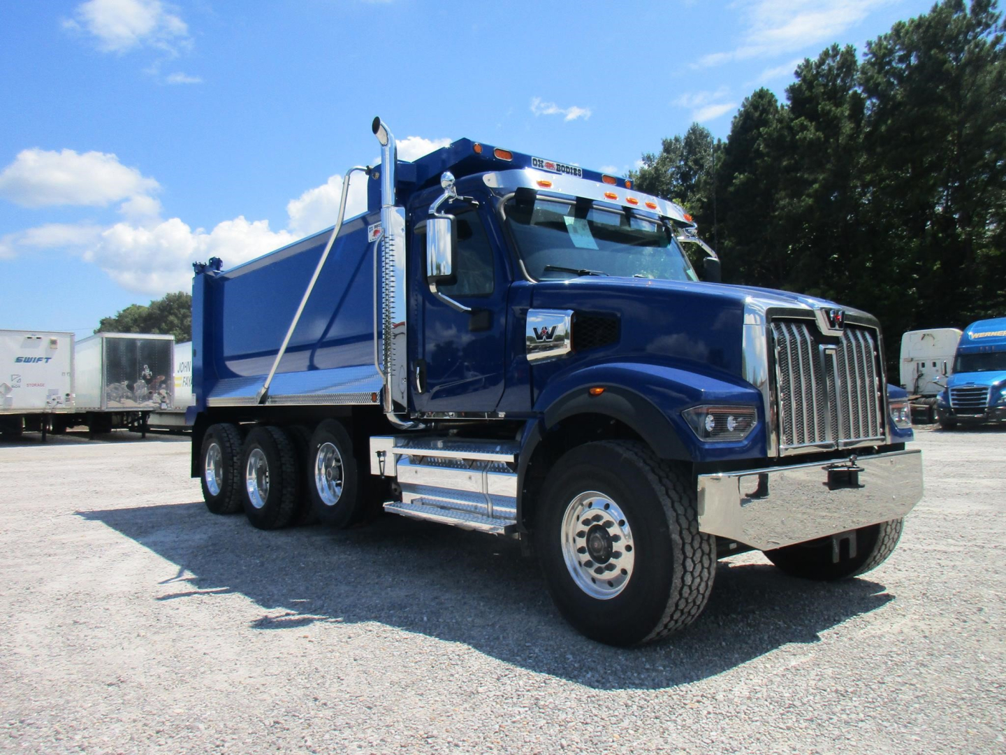 Western Star 49X dump truck in blue, side view showing cab and dual rear axles, chrome bumper, and dump bed.
