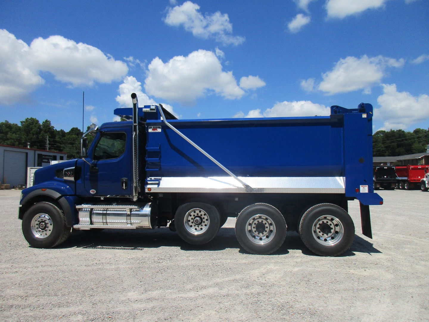Blue Western Star 49X dump truck side view with six wheels and a large dump bed, clear sky.