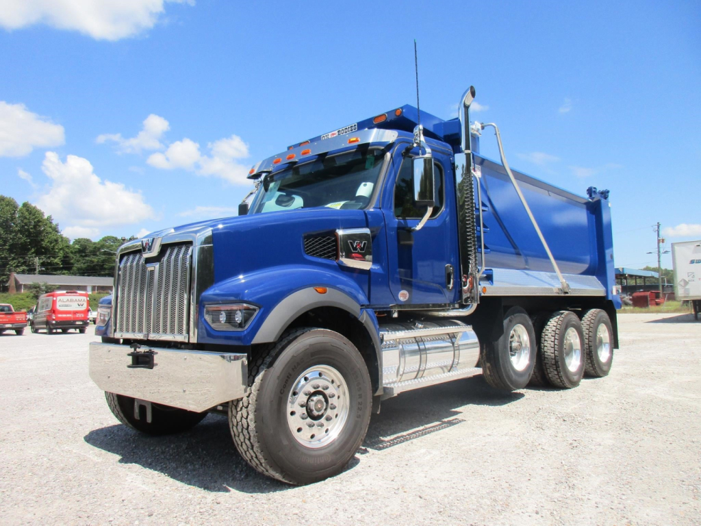 Blue Western Star 49X dump truck in a dealership lot, front three-quarter view, chrome grille, double rear axles, heavy-duty dump bed.