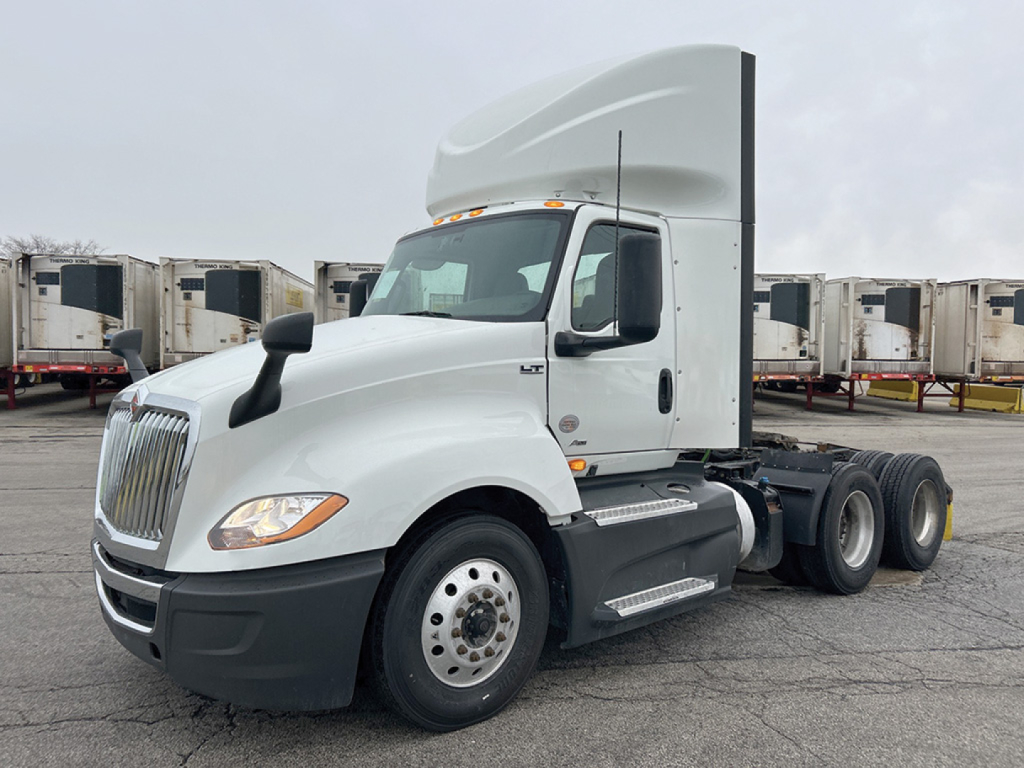 International LT625 daycab tractor in white, side view showing semi-truck with sleeper cab, dual rear axles, and chrome steps.