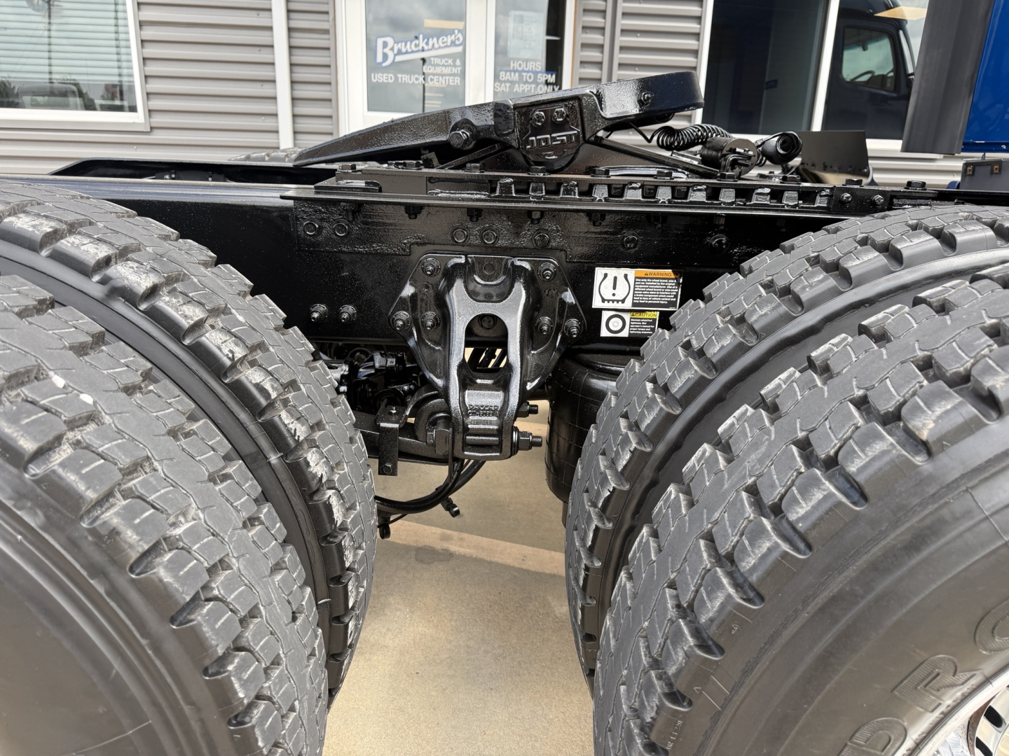 Peterbilt truck chassis showing dual rear axles and fifth wheel hitch in the center with tires and suspension components visible.