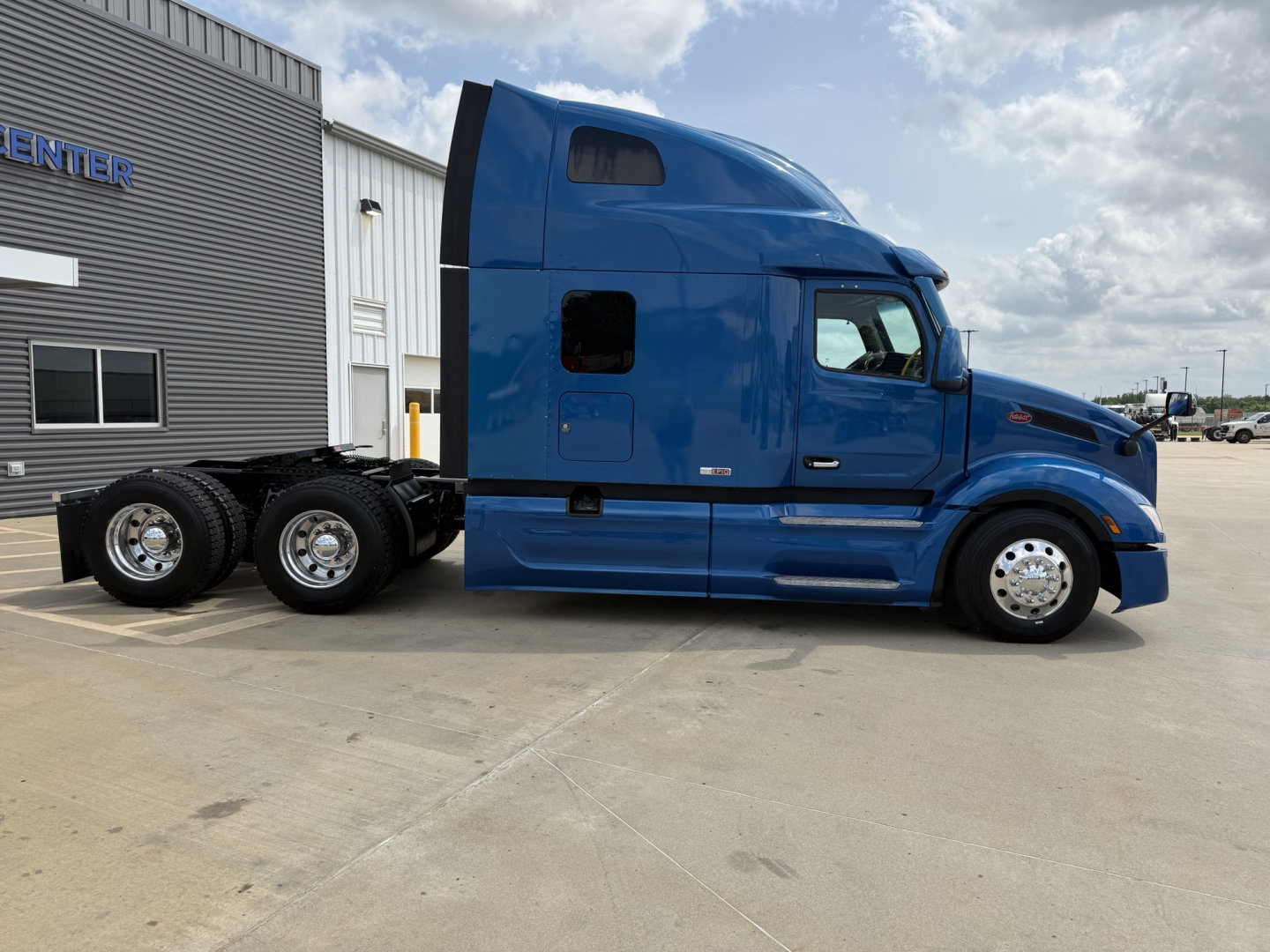 Peterbilt 579 tractor in blue, side view showing sleeper cab and dual rear axles without trailer.