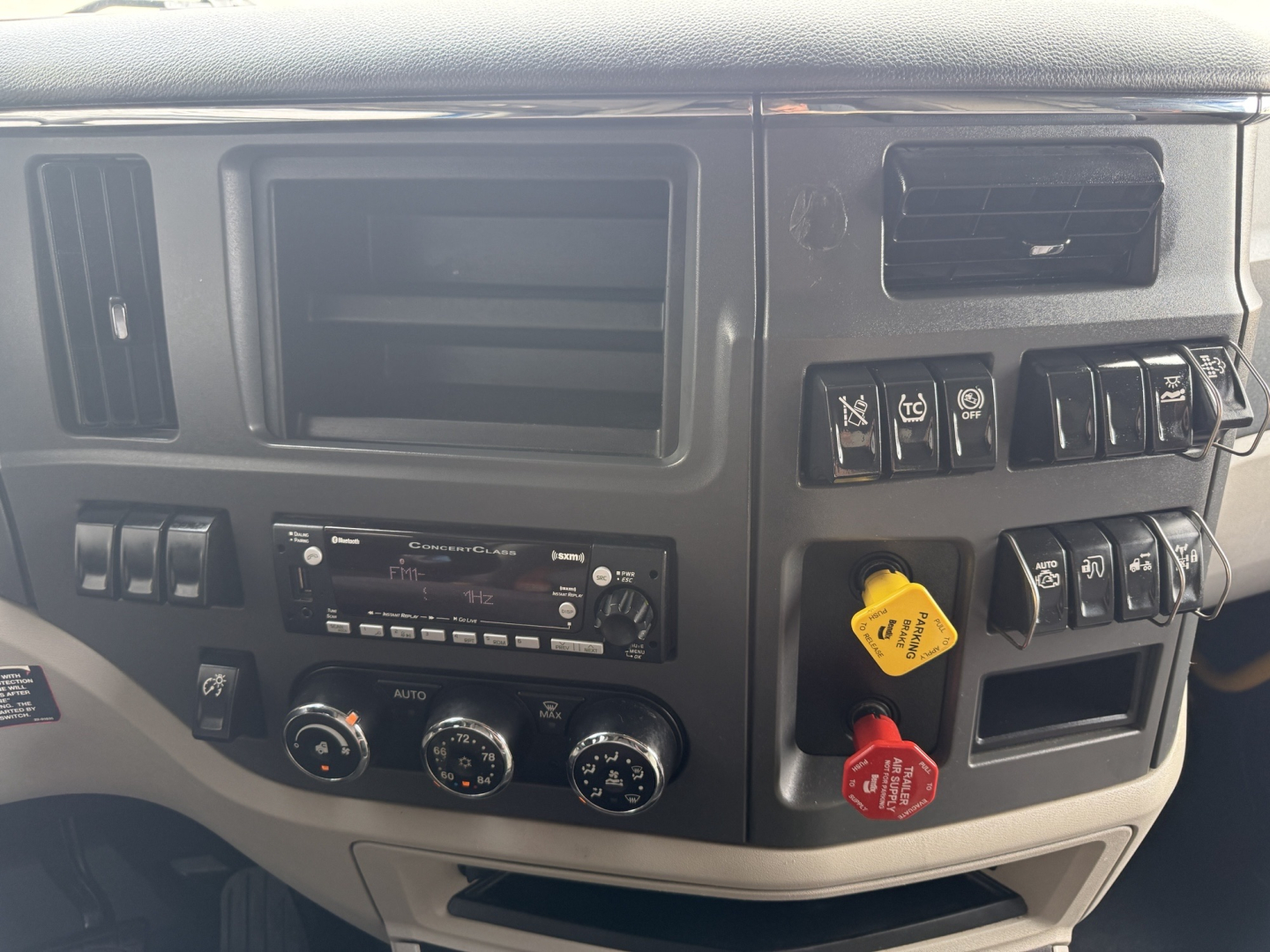 Peterbilt 579 dashboard area showing HVAC controls, radio, dashboard switches, and yellow and red ABS/engine knobs.