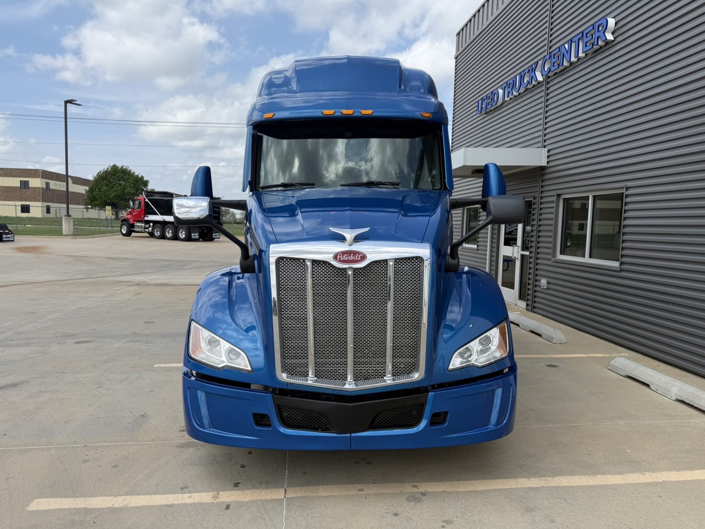 Front view of a blue 2022 Peterbilt 579 truck in a dealership lot with chrome grille, black bumper, and Peterbilt emblem.