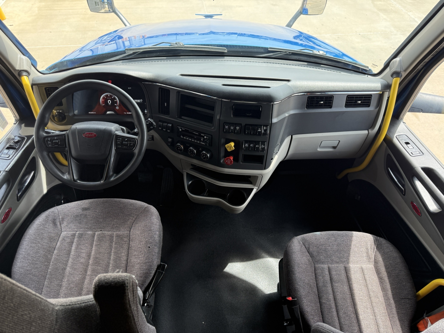 Peterbilt 579 truck interior view from driver seat showing steering wheel, dashboard, and center console with gauges and controls.
