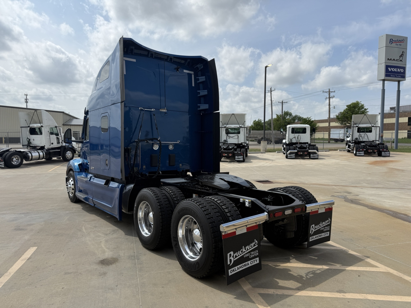 Peterbilt 579 semi-truck tractor rear view showing dual rear axles, blue sleeper cab, black chassis, and mud flaps with company branding.