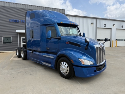 Blue 2022 Peterbilt 579 semi-truck tractor in a lot, cab-over-sleeper with chrome grille, dual rear axles, white wheels, side mirrors, and stock number B3163P visible.