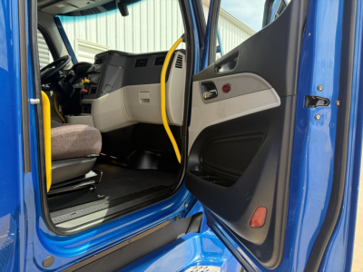 Peterbilt 579 truck interior showing driver door open and blue exterior. Steering wheel and dashboard visible.