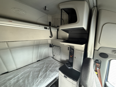 Peterbilt truck cab interior showing sleeper berth with storage compartments and overhead cabinets.